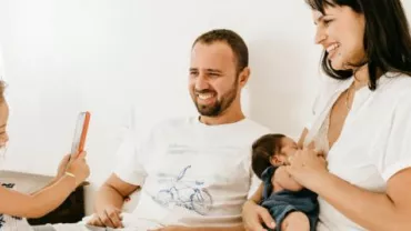 Familie sitzt auf dem Bett, lachende Gesichter.