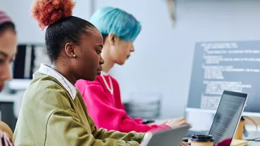 Personen arbeiten konzentriert an Laptops in einem modernen Büro.